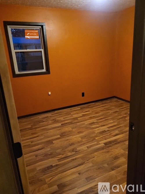 A room with wooden flooring and a window showing a street view.