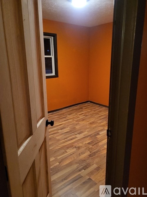 A room with wooden flooring and a door with a black handle.