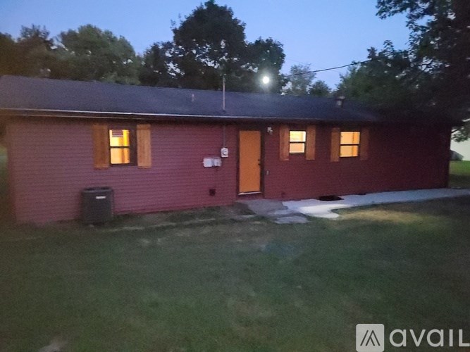 A red building with a brown door and windows is lit by a streetlight.