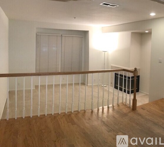A room with a wooden floor and a white railing.