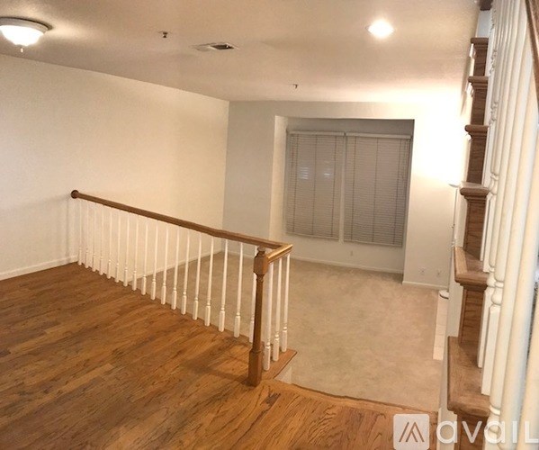 A room with wooden floors and a staircase with white railings.