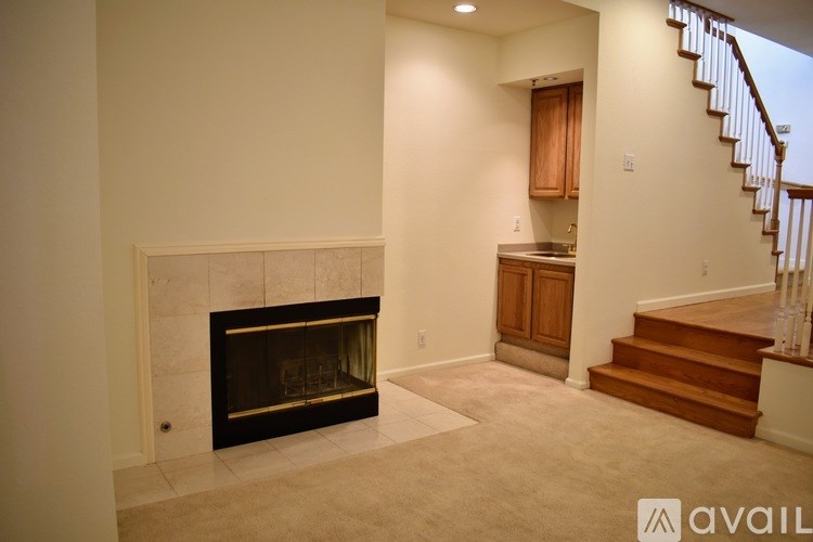 A living room with a fireplace and a staircase.