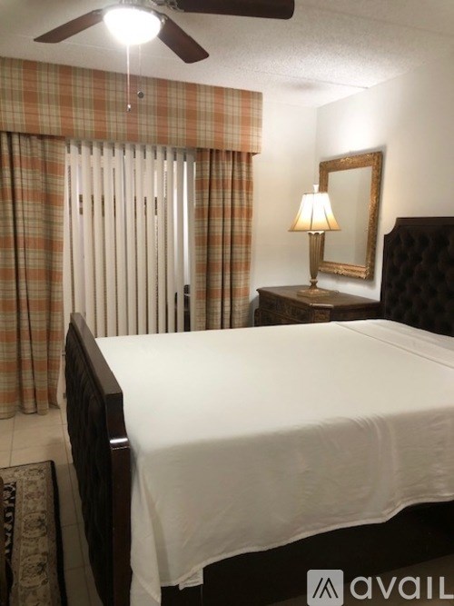 A bedroom with a bed, a ceiling fan, and a lamp.