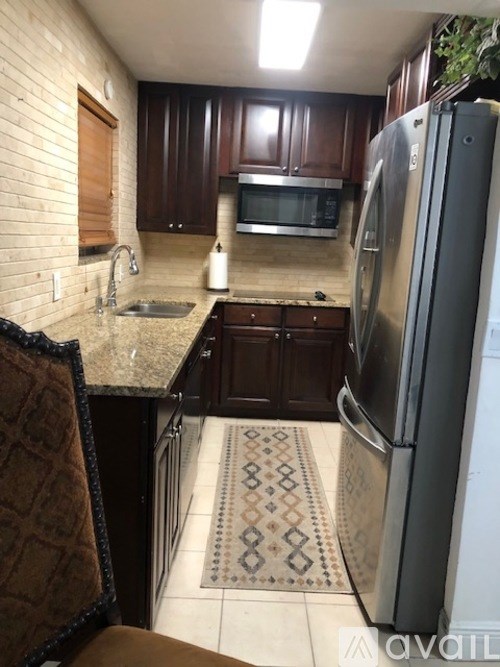 A kitchen with a refrigerator, sink, and cabinets.