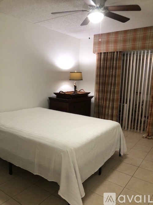 A bed with a white sheet and a lamp on a side table.