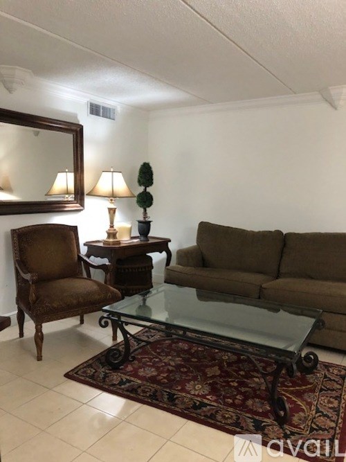 A living room with a brown chair, a glass table, and a couch.