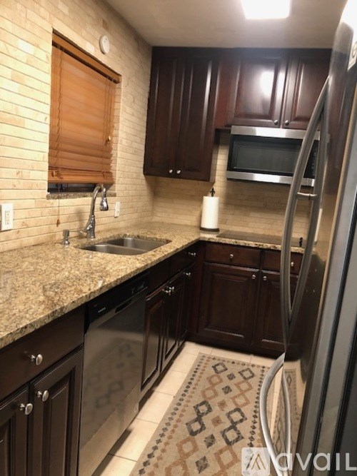 A kitchen with dark wood cabinets and a granite countertop.