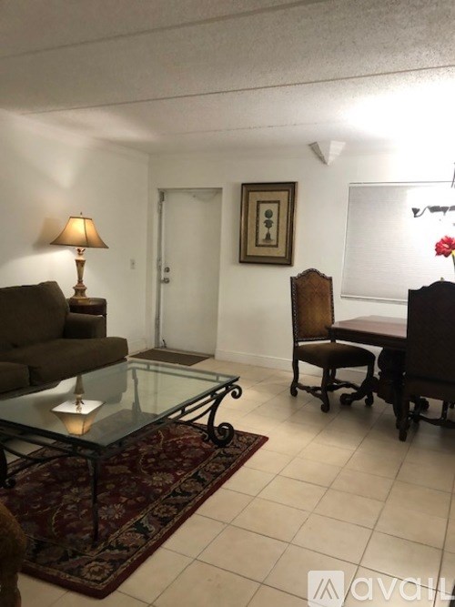 A living room with a glass table and a brown couch.