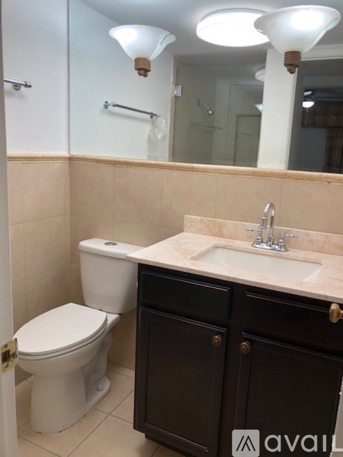 A bathroom with a toilet, sink, and mirror.