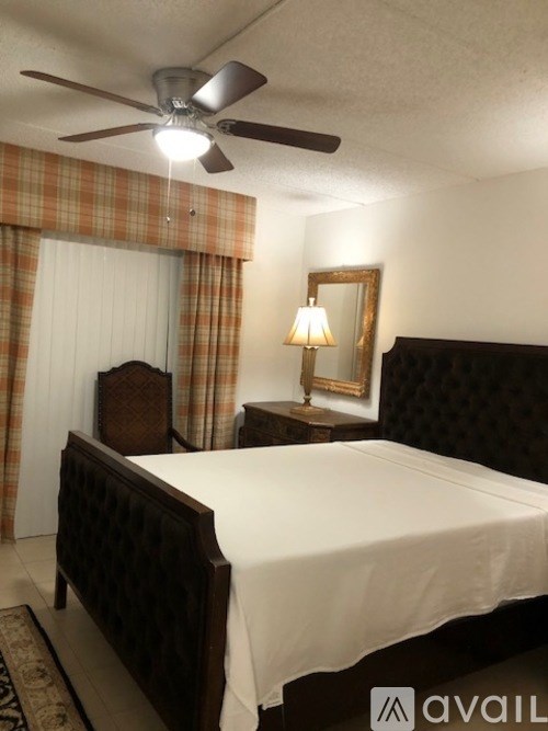 A bedroom with a bed, a ceiling fan, and a mirror.