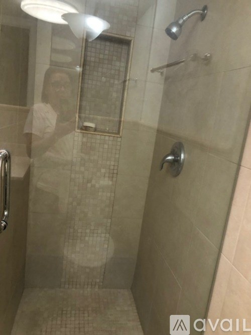 A person is taking a picture of a bathroom with a shower.