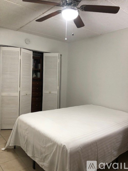 A bedroom with a bed, a ceiling fan, and a wardrobe.