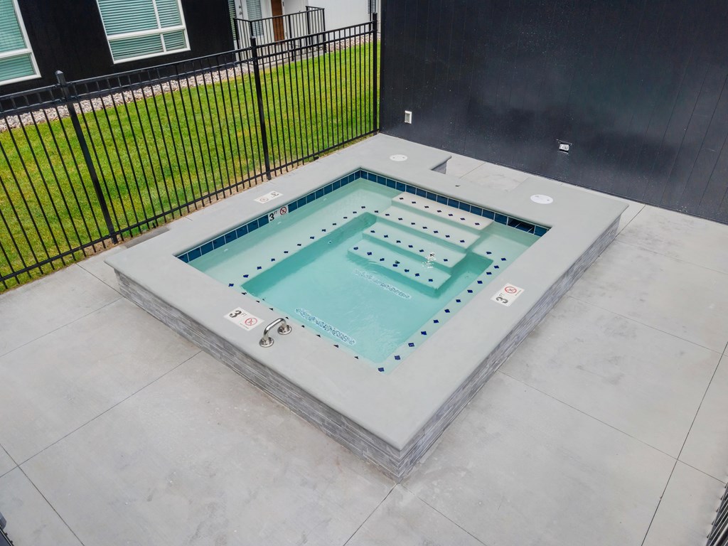 A small rectangular pool with a grey border and a black fence in the background.