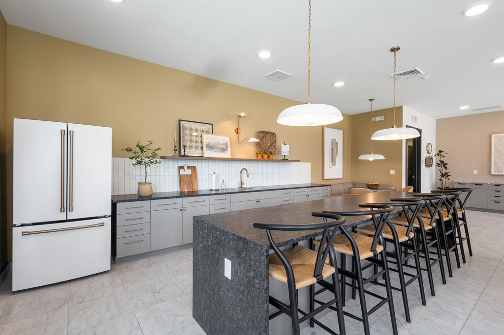 A kitchen with a white fridge and a marble island with chairs.
