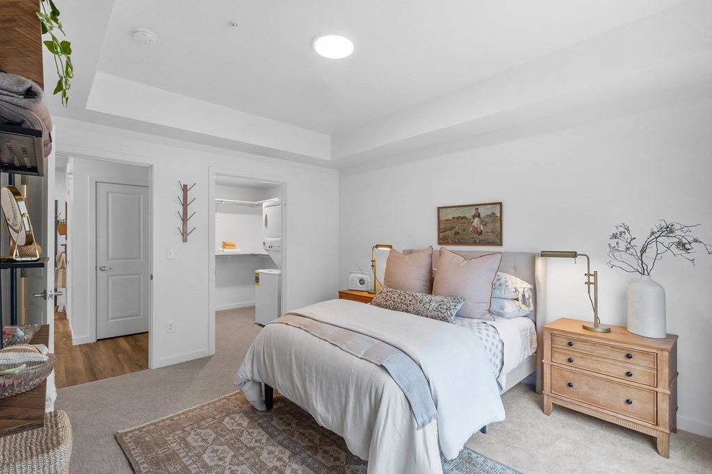 A bedroom with a bed, nightstand, and a painting on the wall.