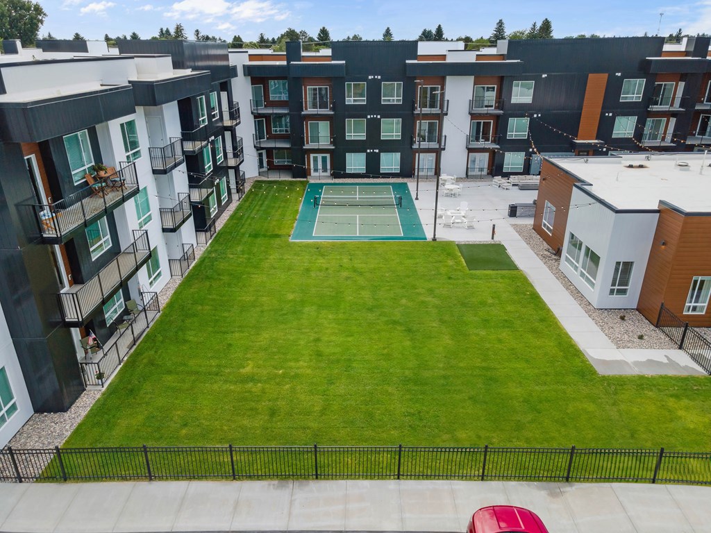 A tennis court is surrounded by apartment buildings.