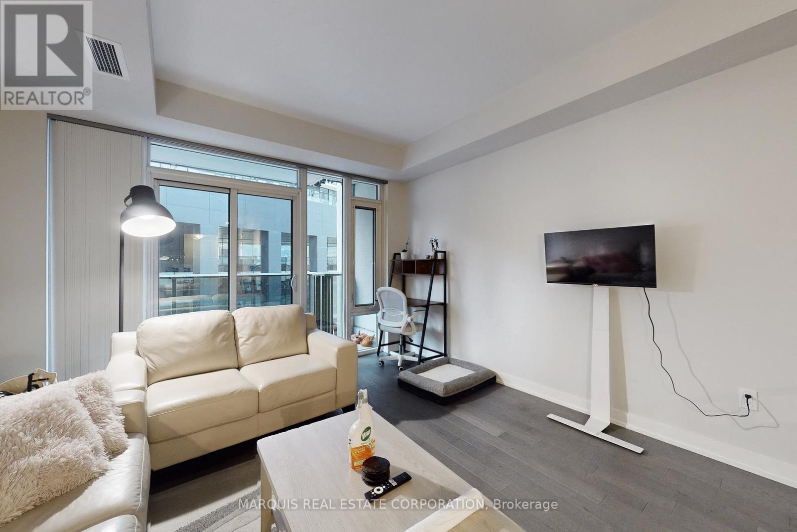 A living room with a white couch and a flat screen TV mounted on the wall.