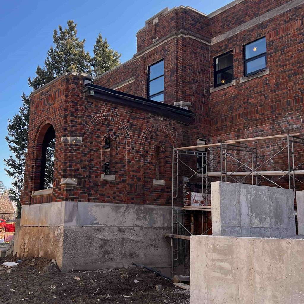 A brick building with a black roof and a large arched window.