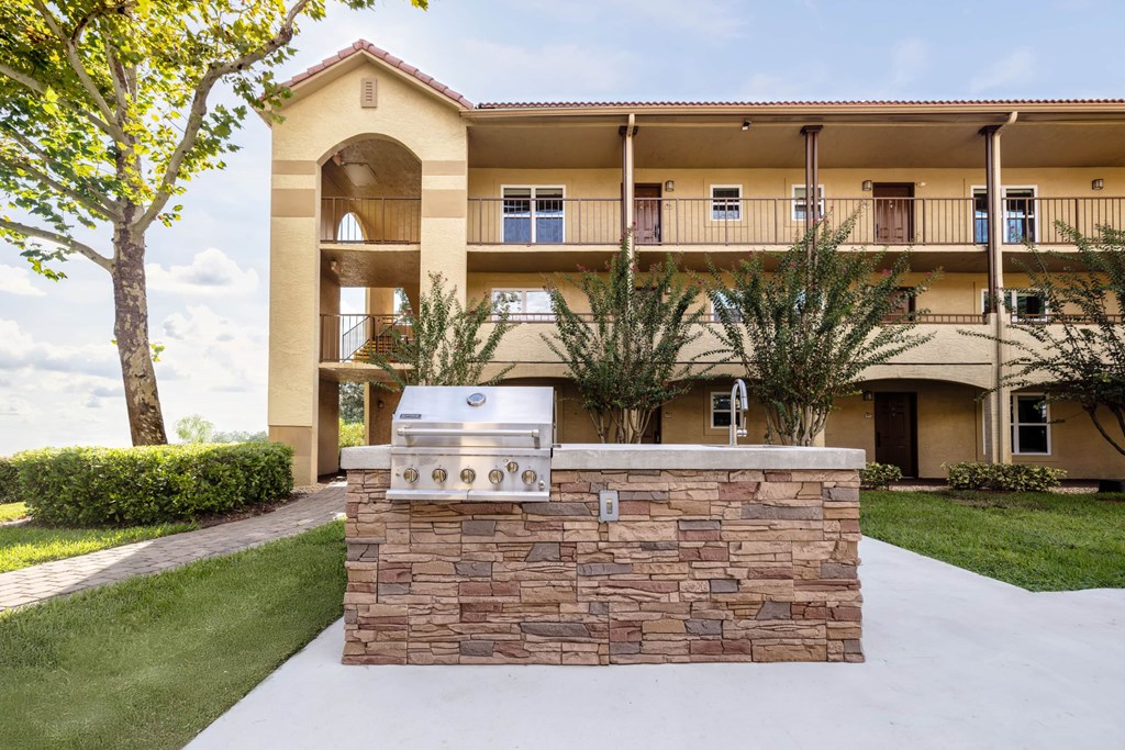 A stone wall with a grill on top of it in front of a building.