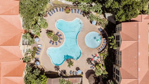 An aerial view of a pool surrounded by trees and buildings.