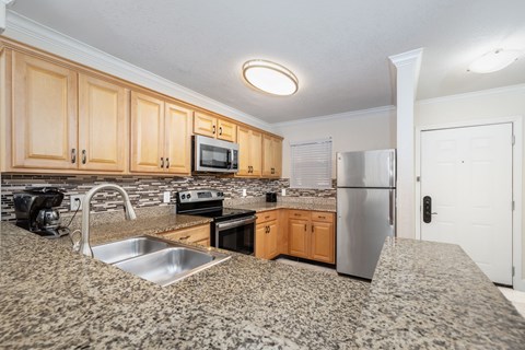 A kitchen with wooden cabinets and a granite countertop.