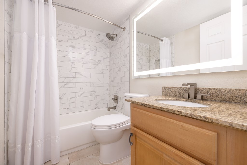 A white toilet sits next to a marble tile wall in a bathroom.
