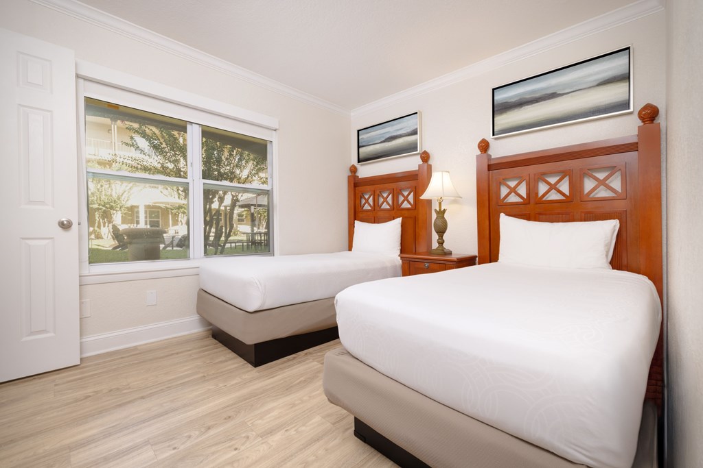 Two beds in a room with wooden headboards and white bedding.