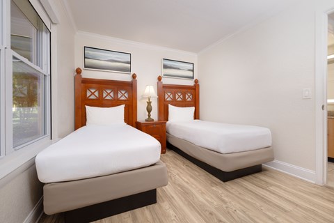 Two twin beds in a room with wooden headboards and white bedding.