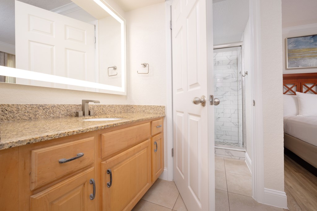A bathroom with a sink, mirror, and wooden cabinets.