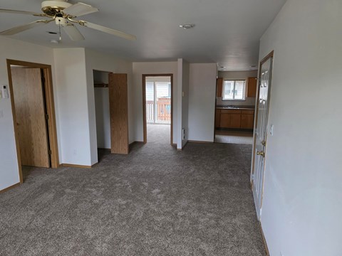 A spacious living room with a ceiling fan and carpeted floor.