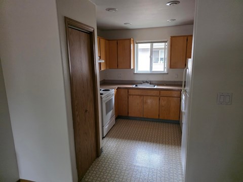 A kitchen with wooden cabinets and a tiled floor.