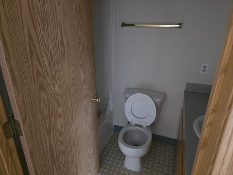 A white toilet in a small bathroom with a wooden door.