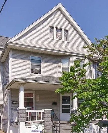 A house with a grey siding and a white porch.
