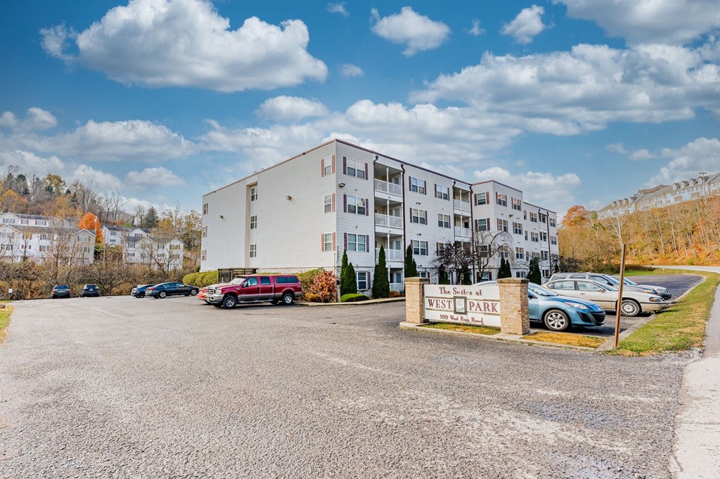 A parking lot in front of a white building with a sign that says "The Shores at West Park.".