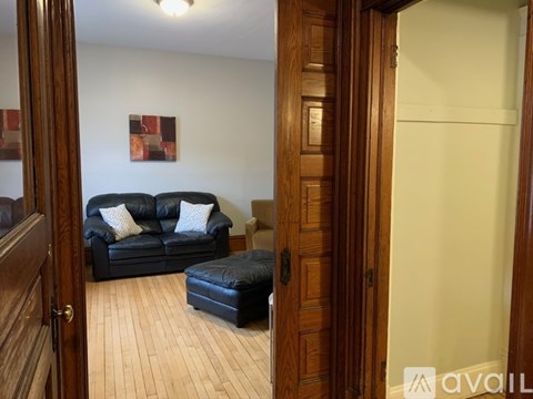 A living room with a black leather couch and ottoman.