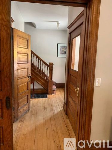 A wooden door is open to a hallway with a staircase.