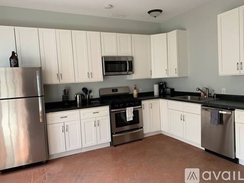 A kitchen with white cabinets and a stainless steel refrigerator.