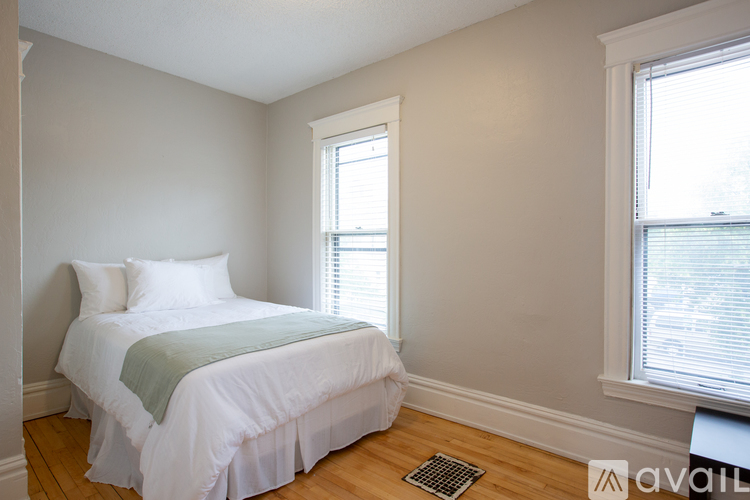 A bedroom with a bed, pillows, and a window.