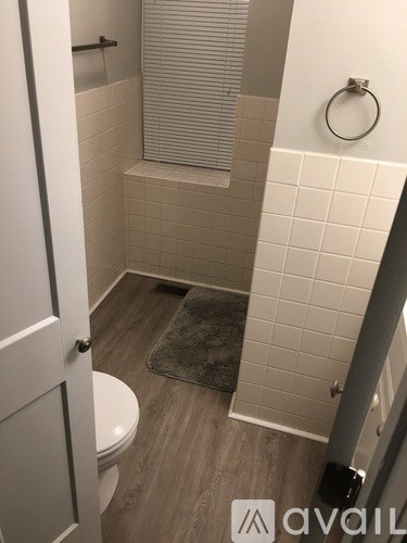 A bathroom with a toilet, a shower, and a towel on the floor.