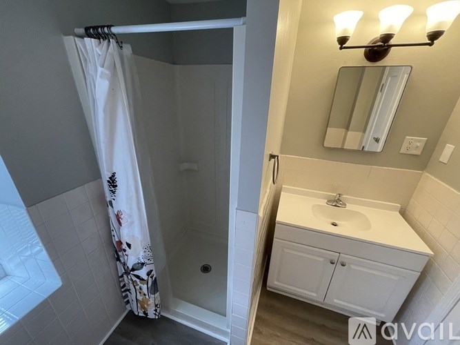 A bathroom with a white sink and a shower with a white curtain.