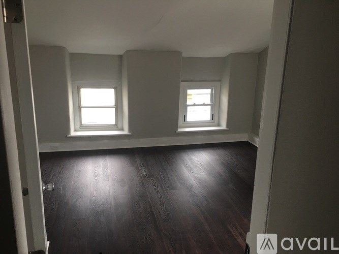 A room with two windows and wooden floors.