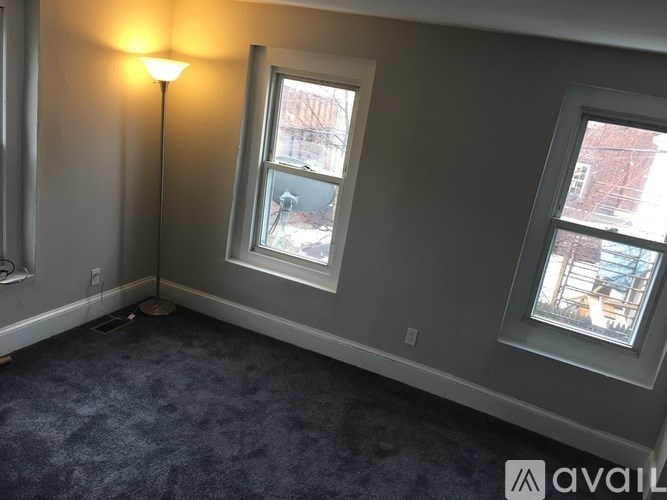 A room with a carpeted floor, a window, and a lamp.