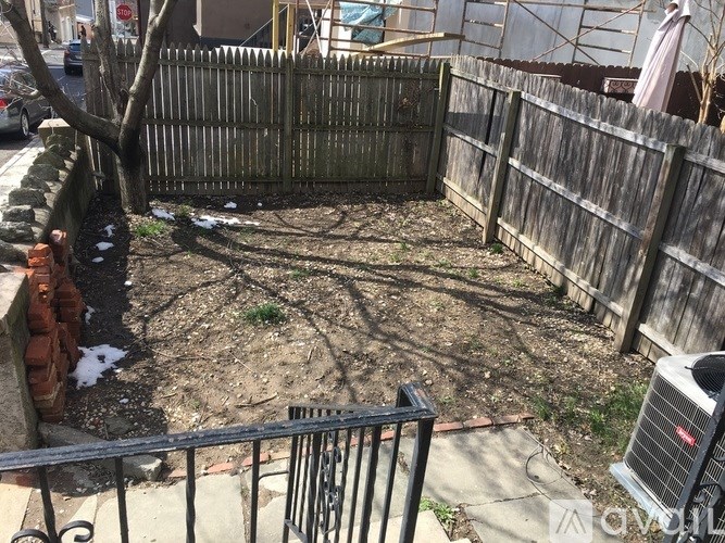 A backyard with a wooden fence and a tree.