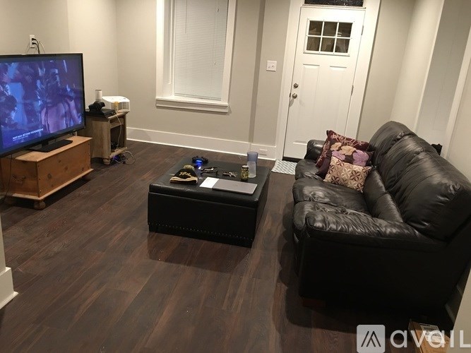 A black leather couch sits in a living room with a TV and a coffee table.
