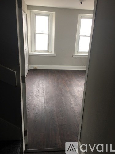 A room with wooden floors and two windows.
