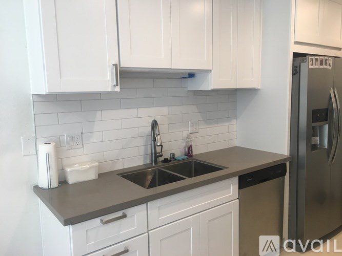 A kitchen with white cabinets and a grey countertop.