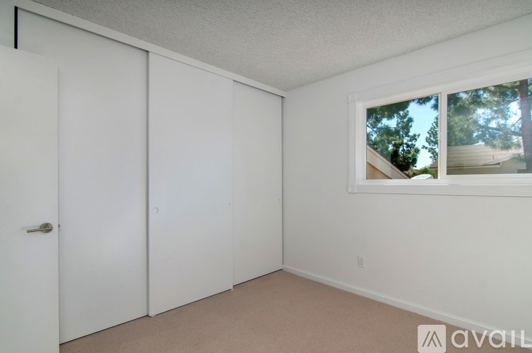 A room with a window showing trees outside.