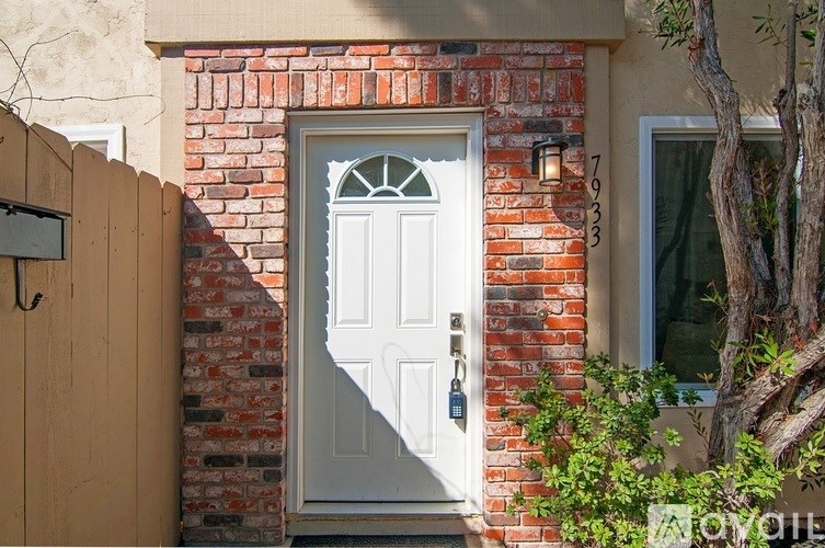 A white door with a black handle is set in a brick wall.