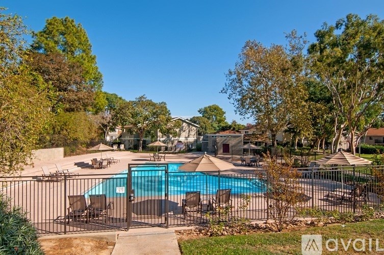 A pool surrounded by trees and a fence with the word "available" written on it.