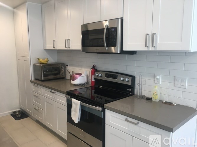 A modern kitchen with white cabinets and black appliances.